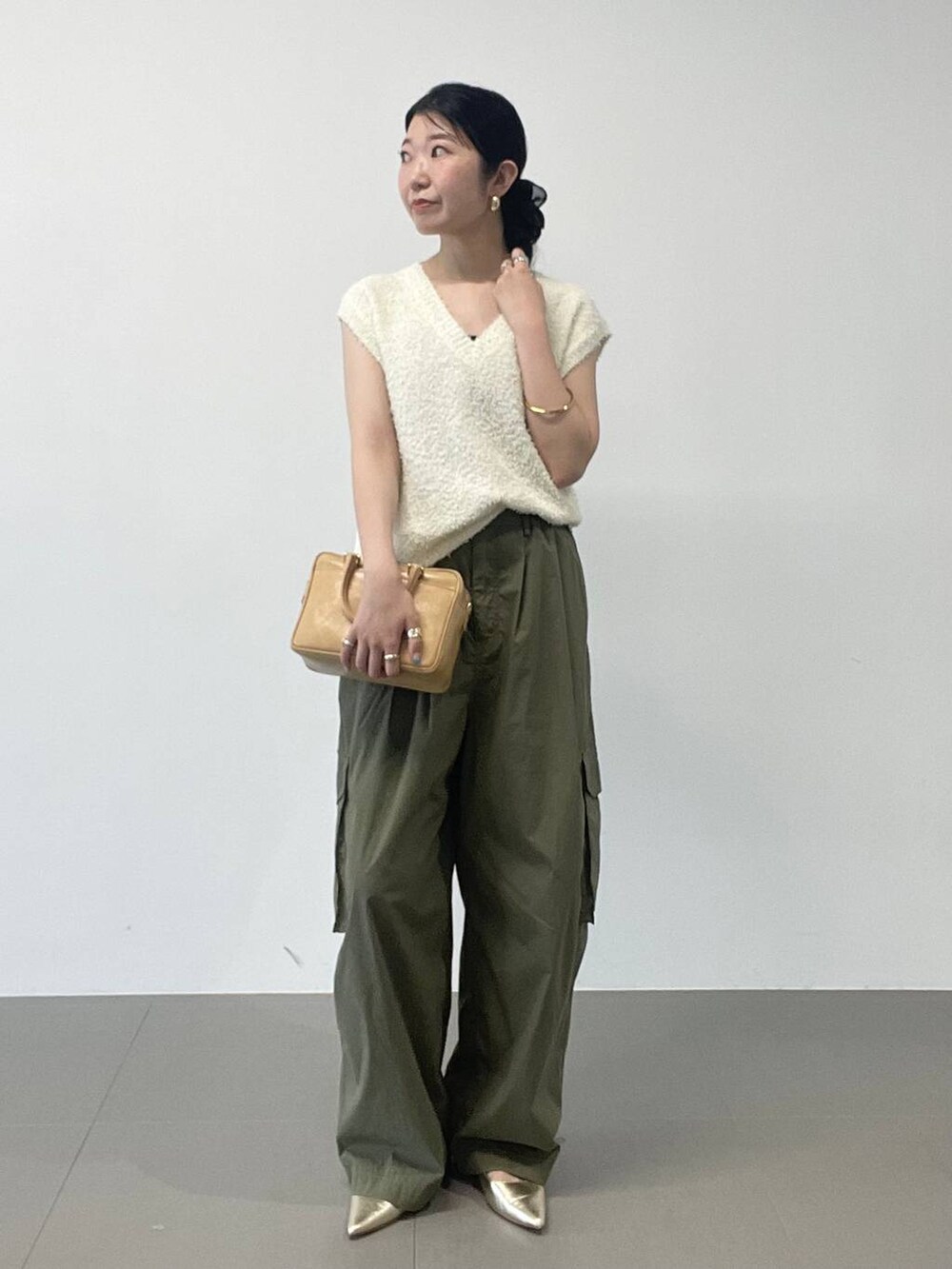 ゴールド系のパンプス、グリーン系のカーゴパンツ、ホワイト系のニット/セーターを着用したレディースの夏コーディネートの2枚目の写真