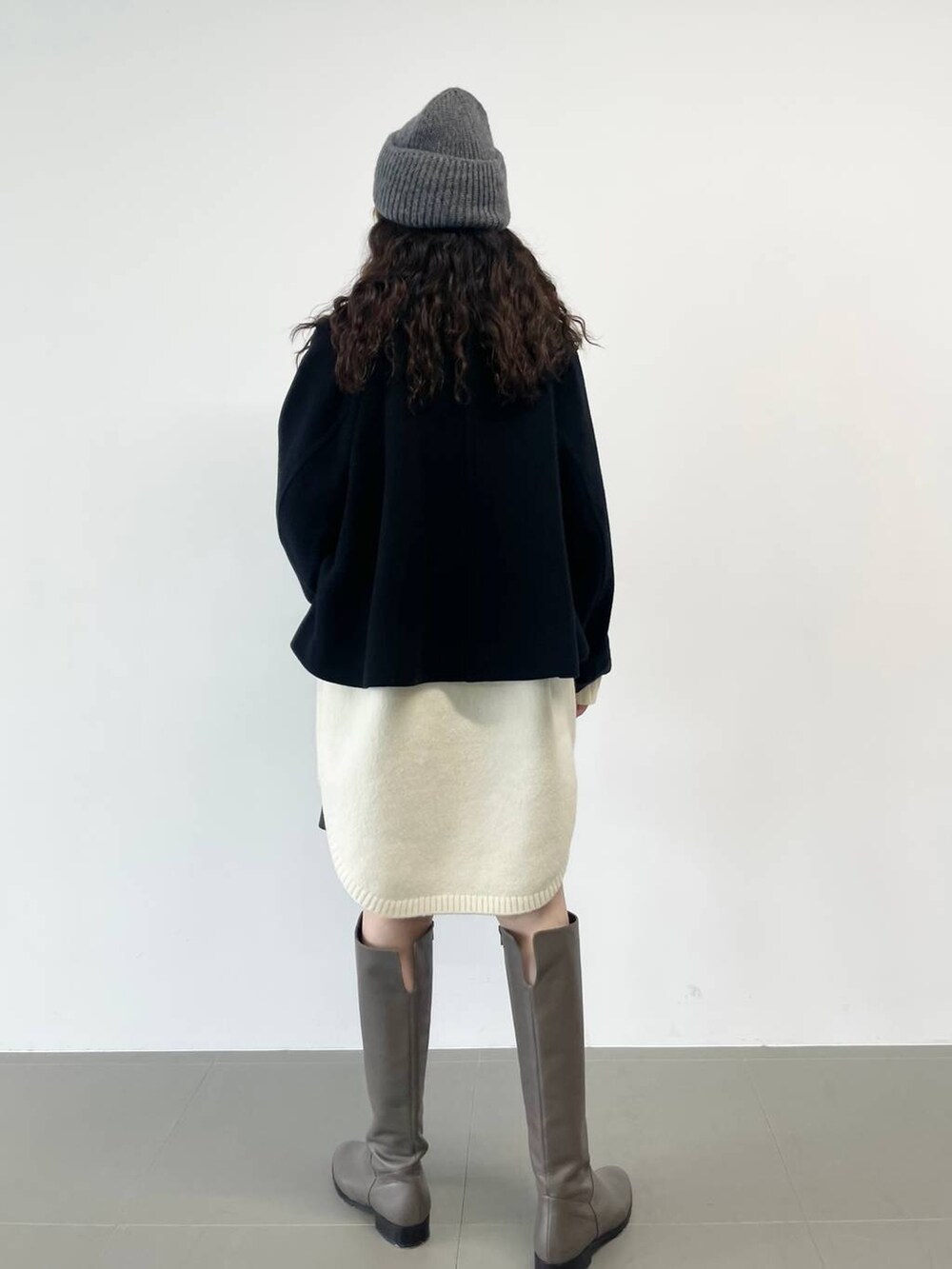 シルバー系のショルダーバッグ、ブラック系のピーコート、ホワイト系のワンピースを着用したレディースの冬コーディネートの4枚目の写真