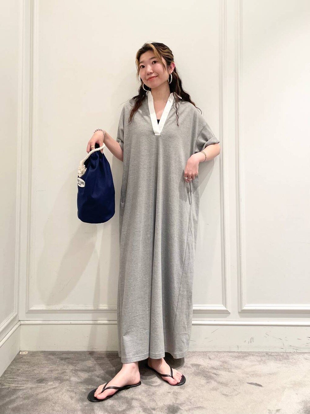 グレー系のワンピース、ブルー系のハンドバッグ、ブラック系のキャミソールを着用したレディースの夏コーディネートの2枚目の写真