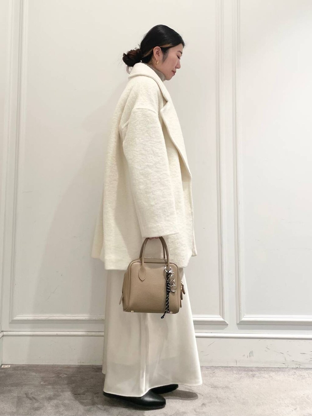 ホワイト系のピーコート、ホワイト系のスカート、ブラウン系のニット/セーターを着用したレディースの冬コーディネートの3枚目の写真