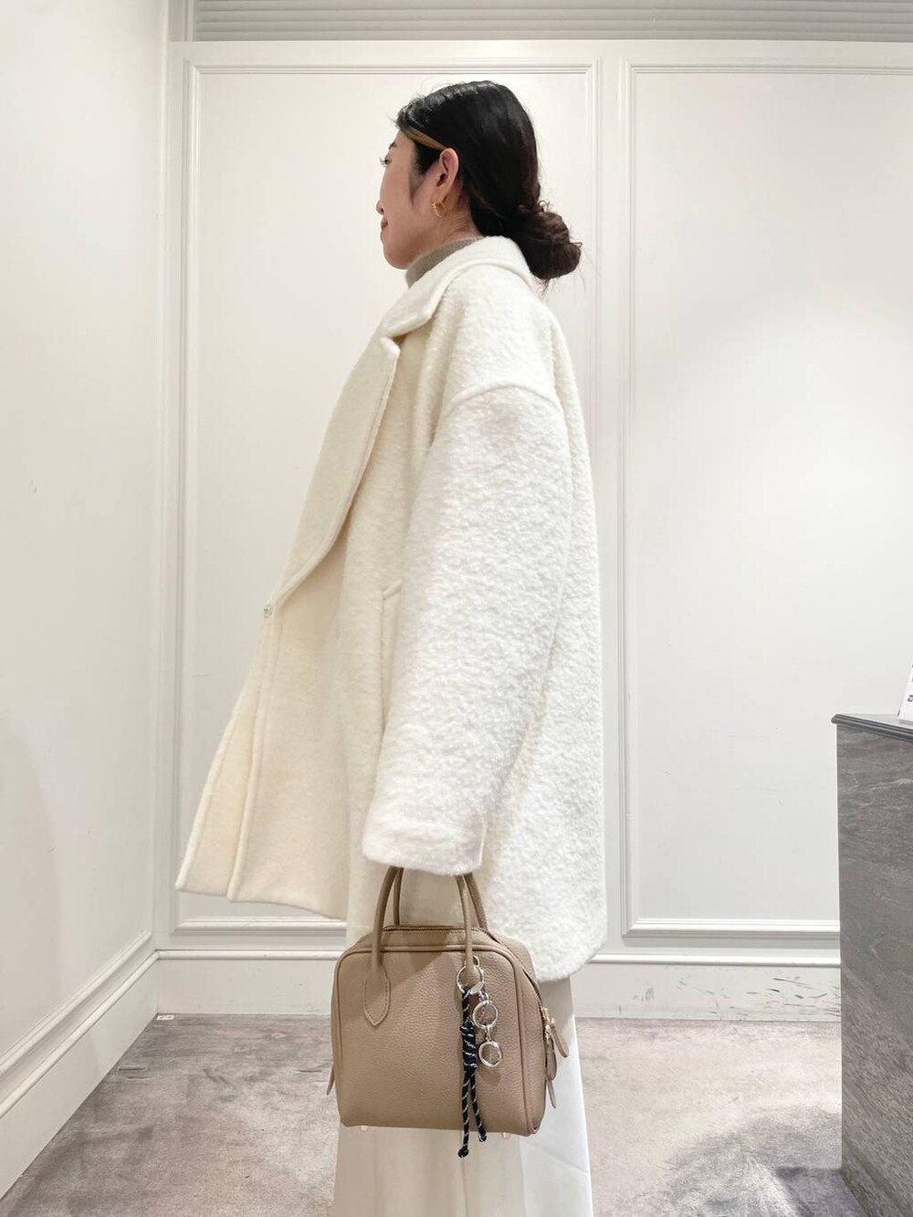 ホワイト系のピーコート、ホワイト系のスカート、ブラウン系のニット/セーターを着用したレディースの冬コーディネートの6枚目の写真