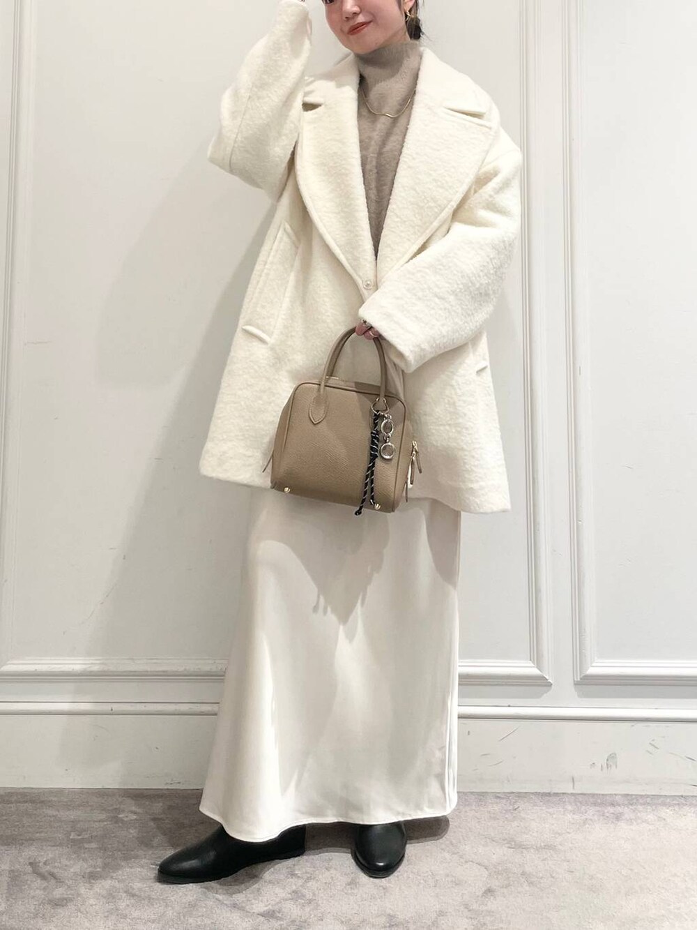 ホワイト系のピーコート、ホワイト系のスカート、ブラウン系のニット/セーターを着用したレディースの冬コーディネートの2枚目の写真
