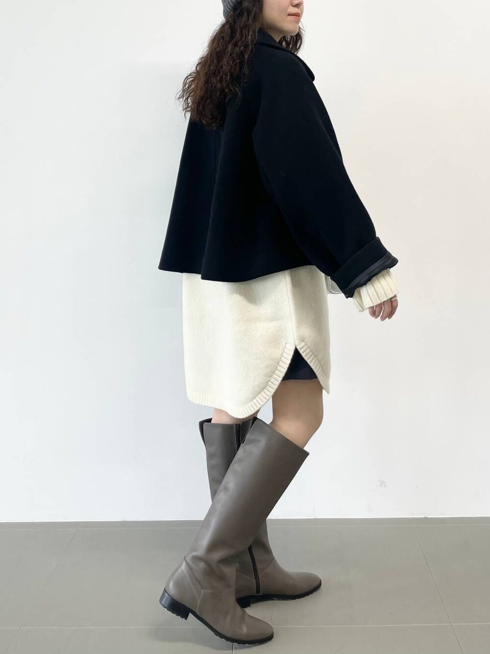 シルバー系のショルダーバッグ、ブラック系のピーコート、ホワイト系のワンピースを着用したレディースの冬コーディネートの3枚目の写真