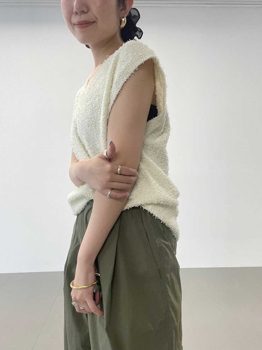 ゴールド系のパンプス、グリーン系のカーゴパンツ、ホワイト系のニット/セーターを着用したレディースの夏コーディネートの7枚目の写真