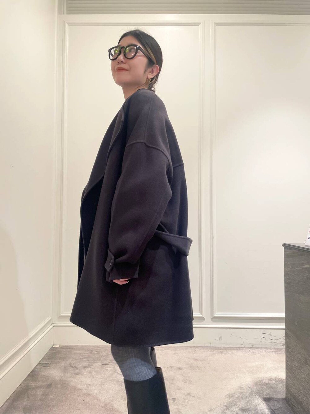 グレー系のピーコート、ブラック系のTシャツ/カットソー、グレー系のニット/セーターを着用したレディースの冬コーディネートの8枚目の写真