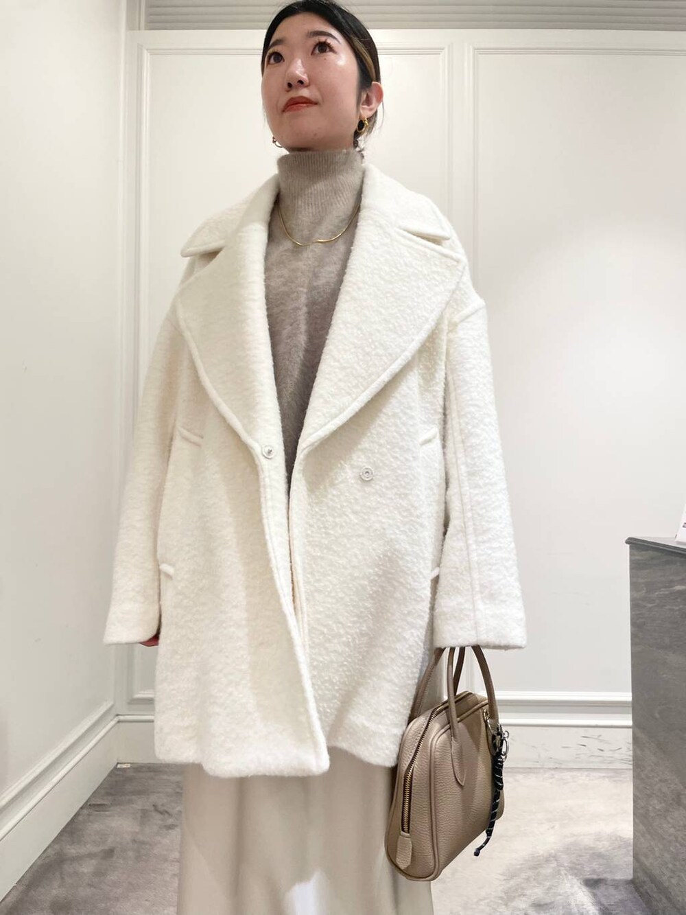 ホワイト系のピーコート、ホワイト系のスカート、ブラウン系のニット/セーターを着用したレディースの冬コーディネートの5枚目の写真