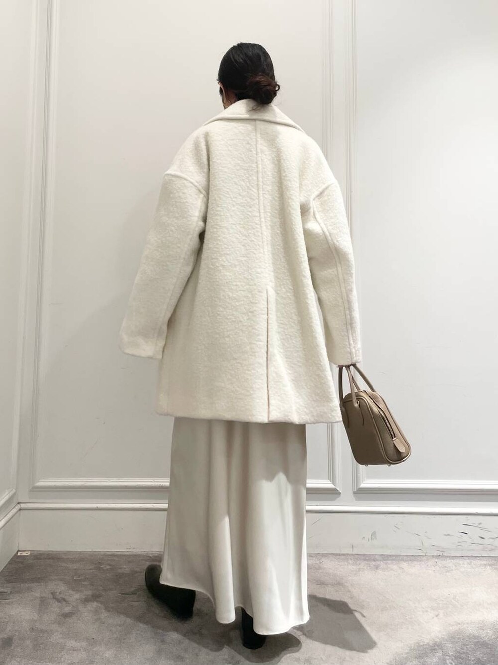 ホワイト系のピーコート、ホワイト系のスカート、ブラウン系のニット/セーターを着用したレディースの冬コーディネートの4枚目の写真