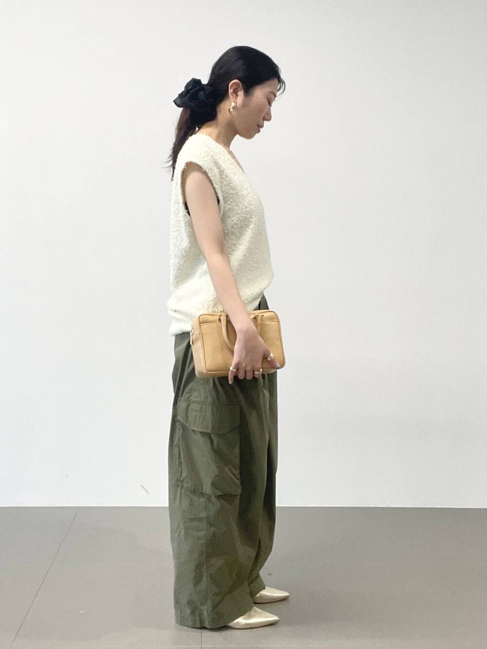 ゴールド系のパンプス、グリーン系のカーゴパンツ、ホワイト系のニット/セーターを着用したレディースの夏コーディネートの3枚目の写真