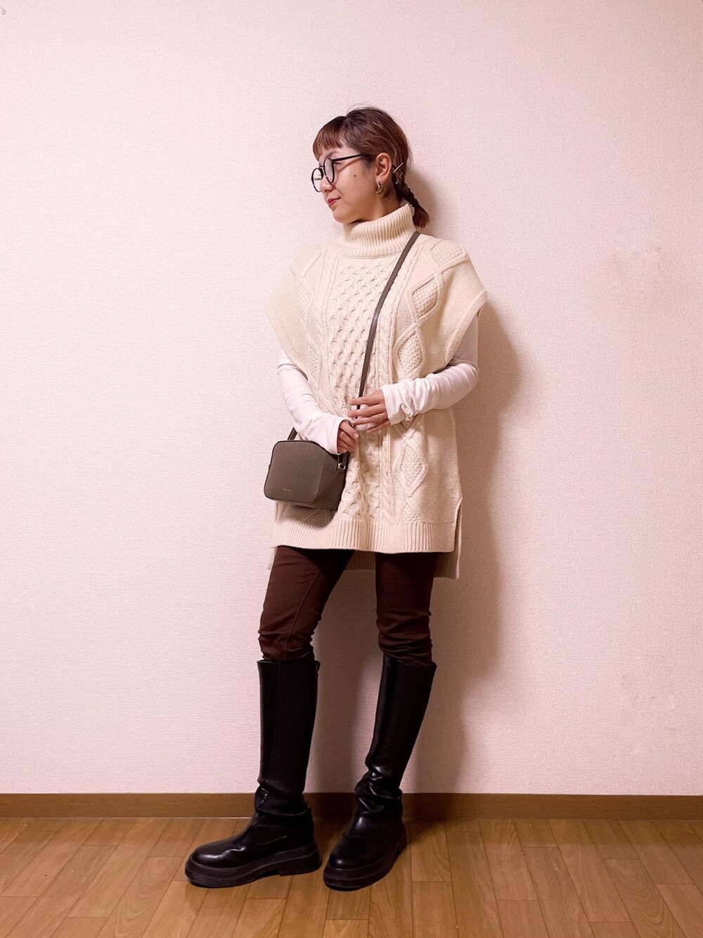 グリーン系のショルダーバッグ、ホワイト系のベスト、ブラウン系のパンツを着用したレディースの冬コーディネートの2枚目の写真