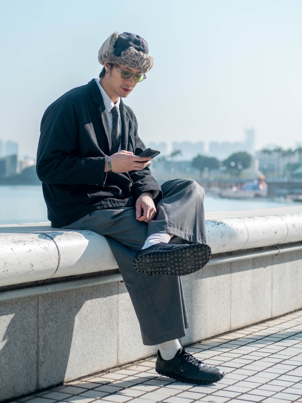 ブラック系のチェスターコート、ブラック系のネクタイ、グレー系のスーツパンツを着用したメンズの冬コーディネートの2枚目の写真