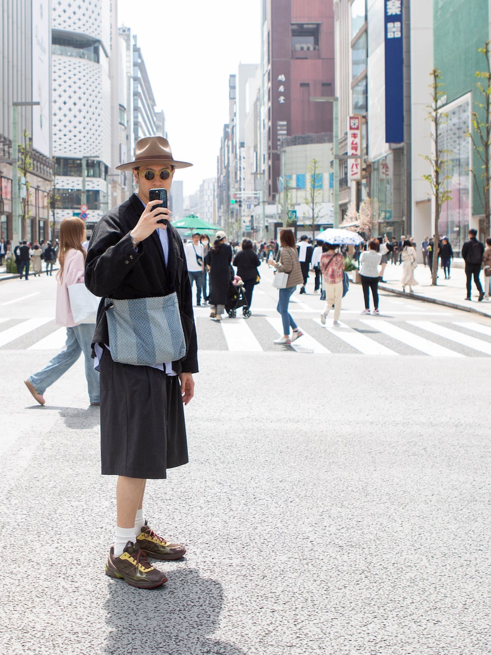 ブラック系のテーラードジャケット、ブラウン系のスニーカー、ブラック系のカーゴパンツを着用したメンズの春コーディネートの3枚目の写真