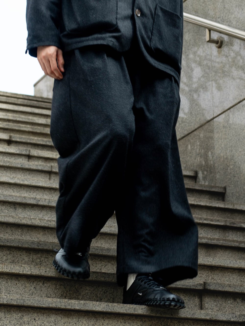 ブラック系のテーラードジャケット、ブラック系のスラックス、ブラック系のスニーカーを着用したメンズの冬コーディネートの4枚目の写真