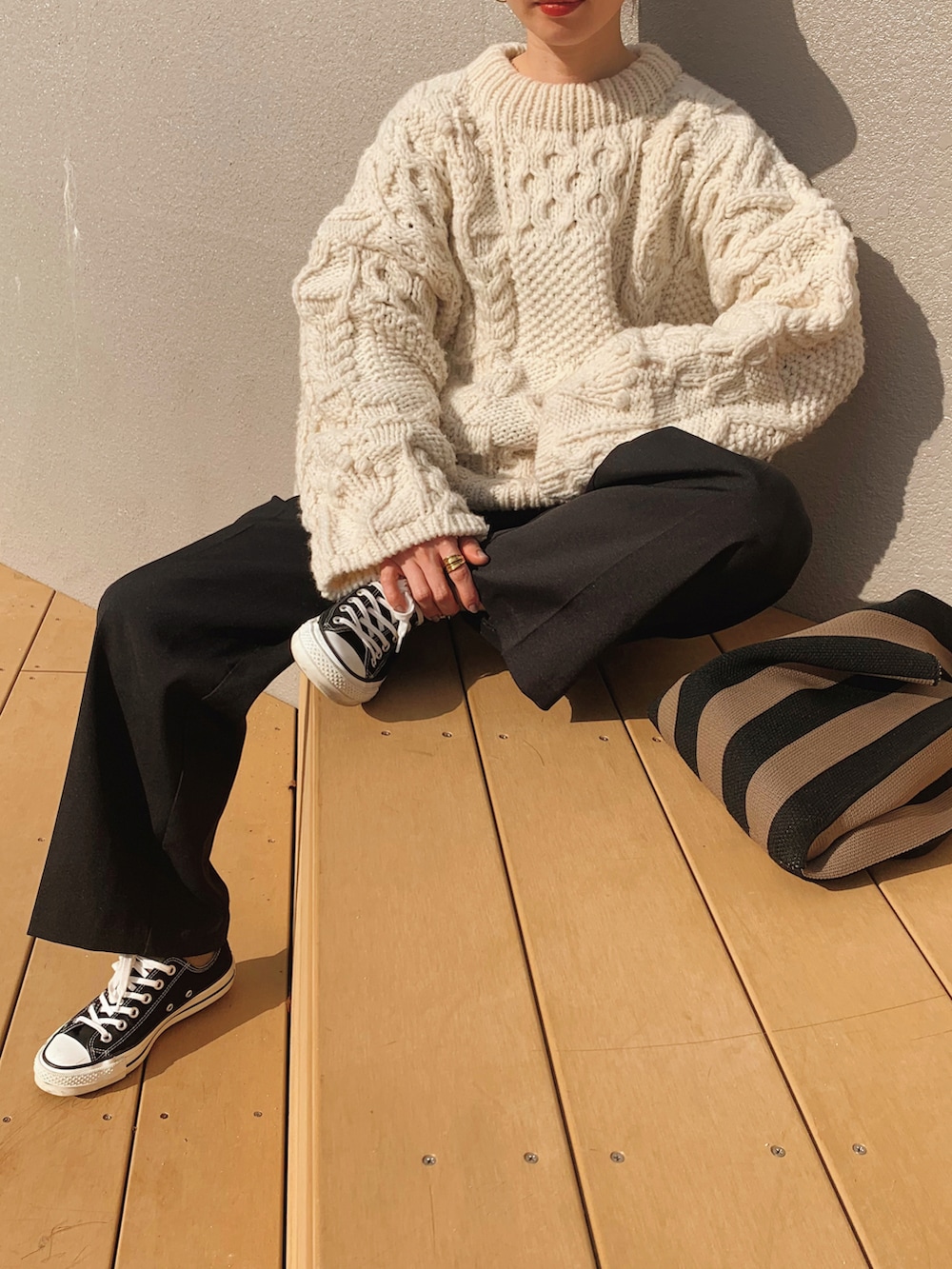 ブラック系のスラックス、ホワイト系のニット/セーター、ブラック系のスニーカーを着用したレディースの冬コーディネートの3枚目の写真