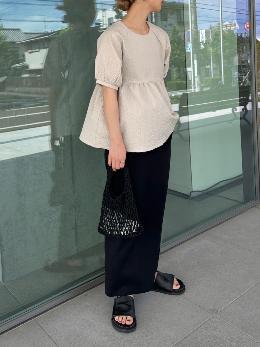 ベージュ系のシャツ/ブラウス、ブラック系のスカート、ブラック系のハンドバッグを着用したレディースの夏コーディネートの2枚目の写真