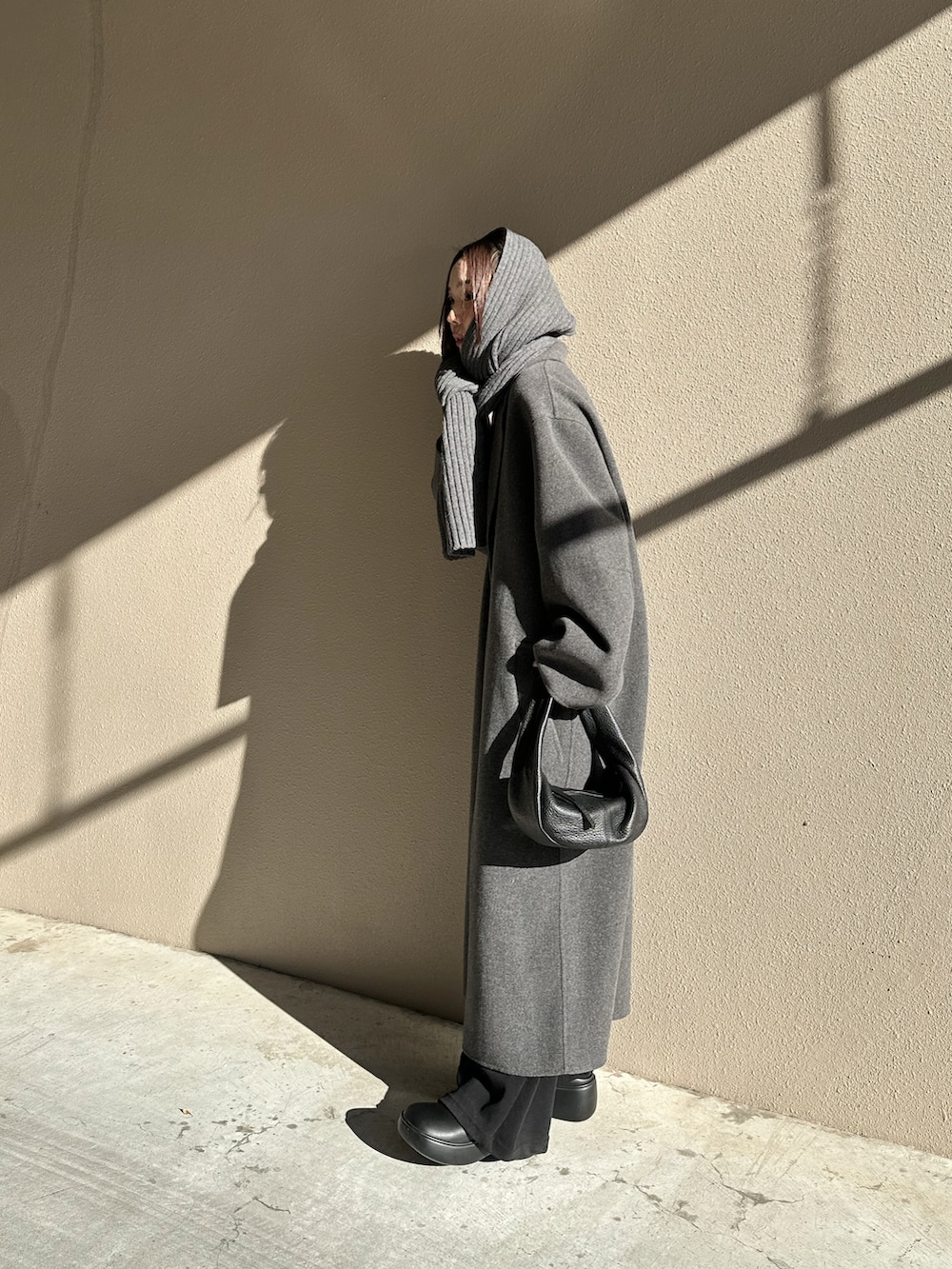 グレー系のステンカラーコート、ブラック系のローファー、ブラック系のハンドバッグを着用したレディースの冬コーディネートの5枚目の写真