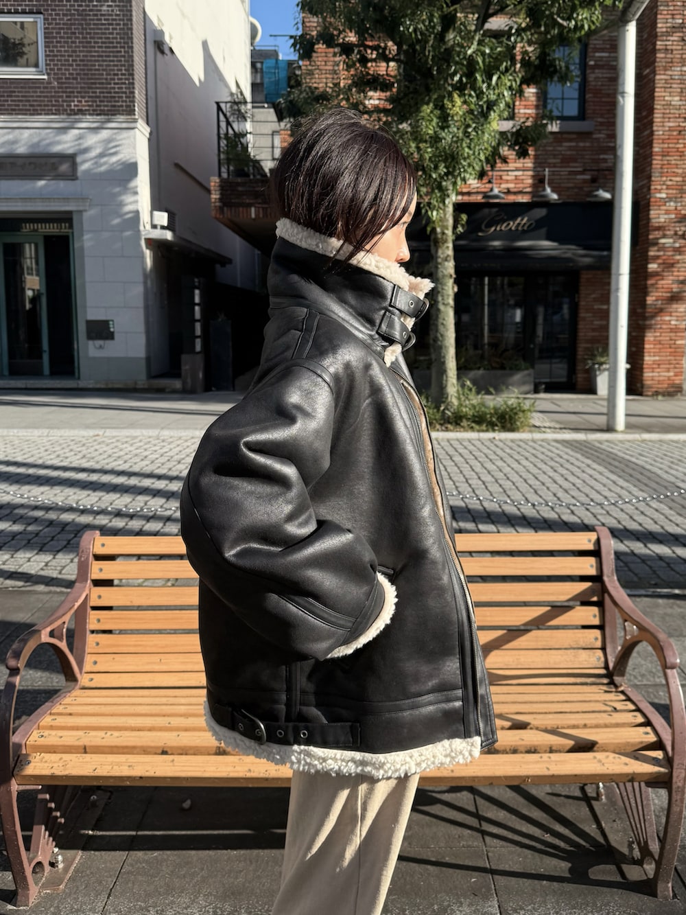 ベージュ系のワンピース、ブラック系のブルゾン、ブラック系のスニーカーを着用したレディースの秋コーディネートの5枚目の写真