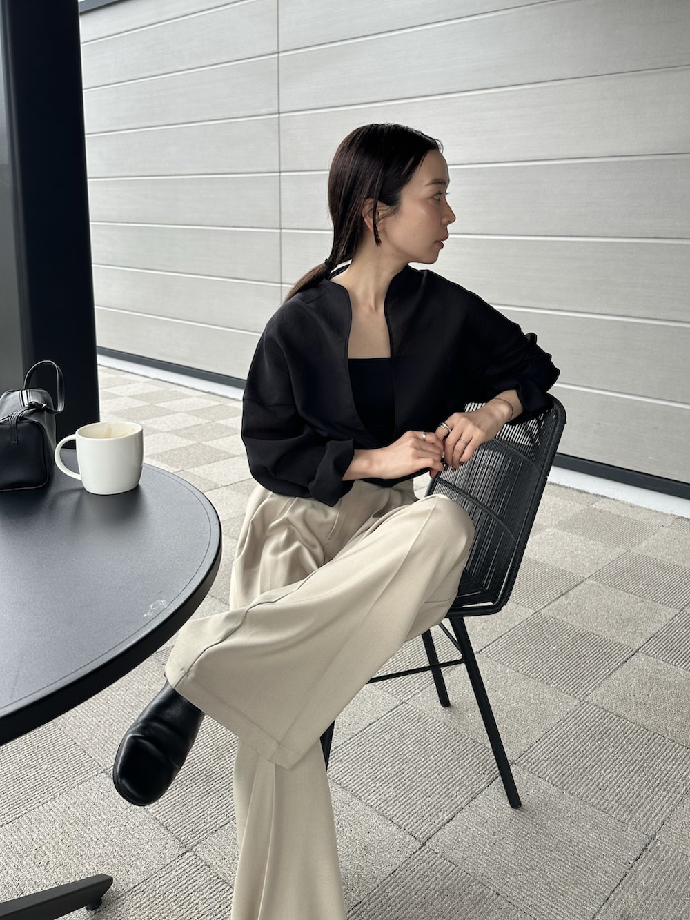 ベージュ系のスラックス、ブラック系のシャツ/ブラウス、ブラック系のスリッポンを着用したレディースの春コーディネートの2枚目の写真