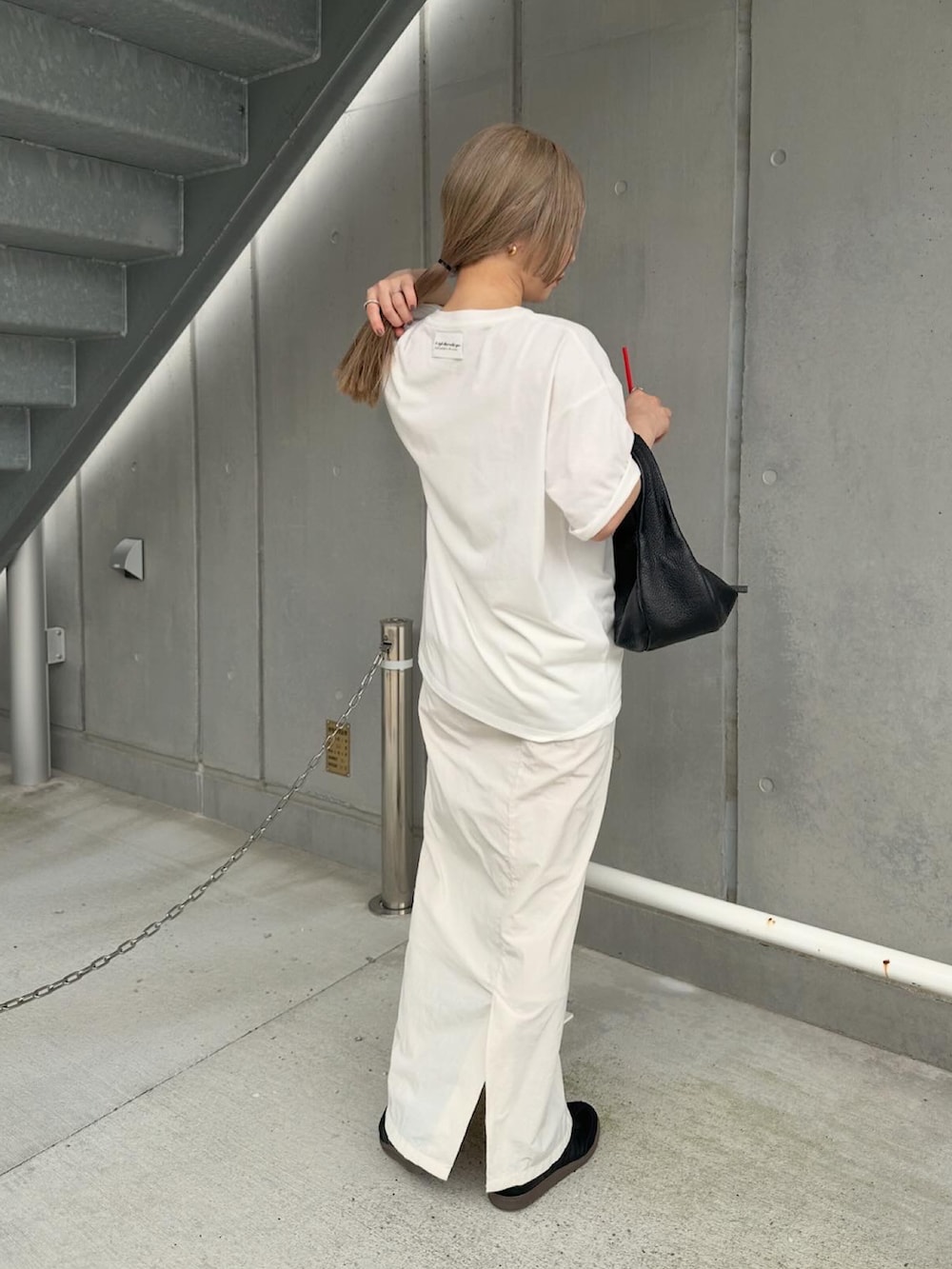 ホワイト系のTシャツ/カットソー、ホワイト系のスカート、ブラック系のスニーカーを着用したレディースの夏コーディネートの3枚目の写真