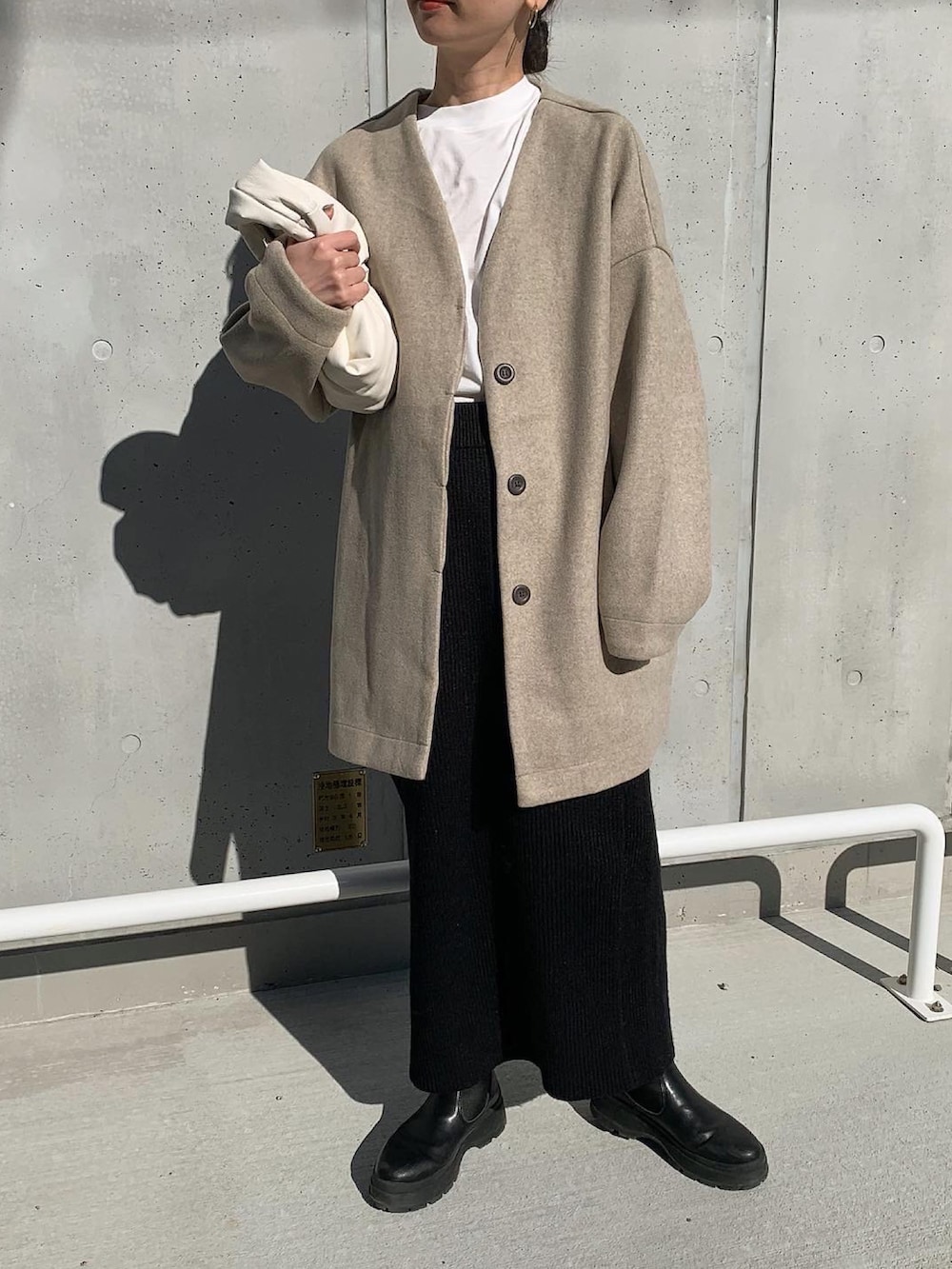 ベージュ系のノーカラーコート、ホワイト系のTシャツ/カットソー、ブラック系のセットアップを着用したレディースの冬コーディネートの3枚目の写真