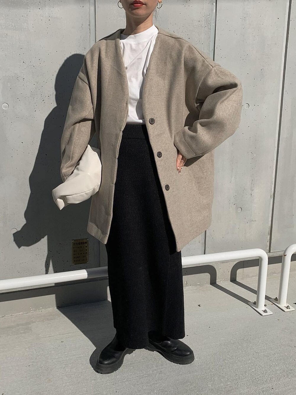 ベージュ系のノーカラーコート、ホワイト系のTシャツ/カットソー、ブラック系のセットアップを着用したレディースの冬コーディネートの4枚目の写真