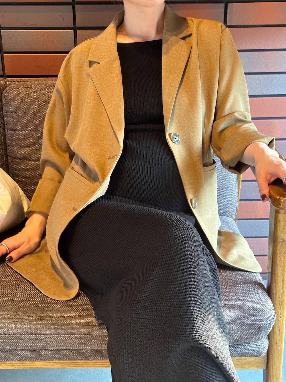 ブラウン系のテーラードジャケット、ブラック系のワンピース、ホワイト系のハンドバッグを着用したレディースの春コーディネートの3枚目の写真