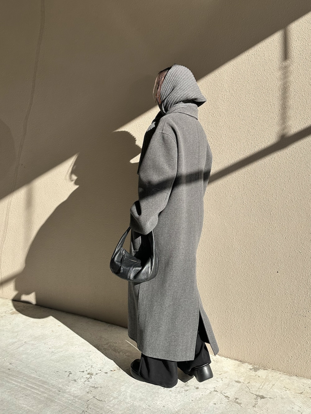 グレー系のステンカラーコート、ブラック系のローファー、ブラック系のハンドバッグを着用したレディースの冬コーディネートの3枚目の写真