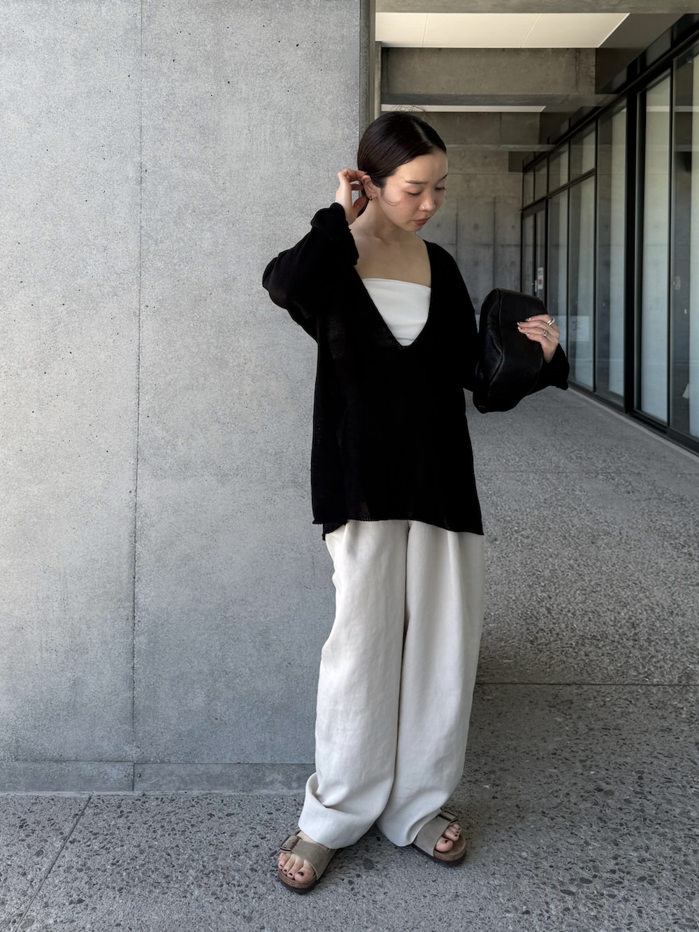 ブラック系のニット/セーター、ホワイト系のその他パンツ、ベージュ系のサンダルを着用したレディースの夏コーディネートの4枚目の写真