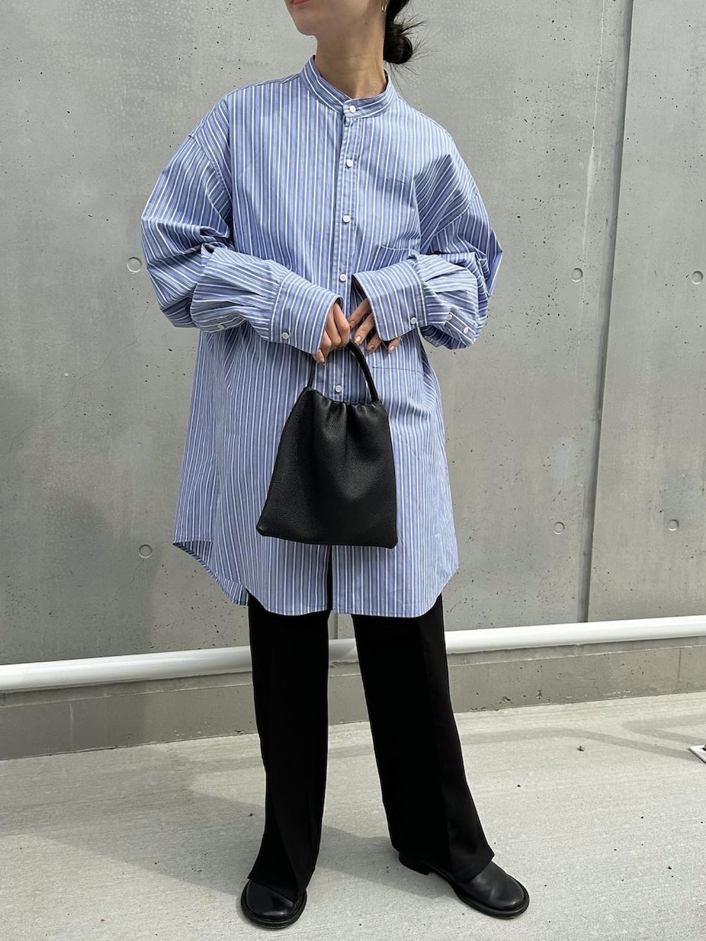 ブラック系のパンツ、ブルー系のシャツ/ブラウス、ブラック系のハンドバッグを着用したレディースの春コーディネートの3枚目の写真