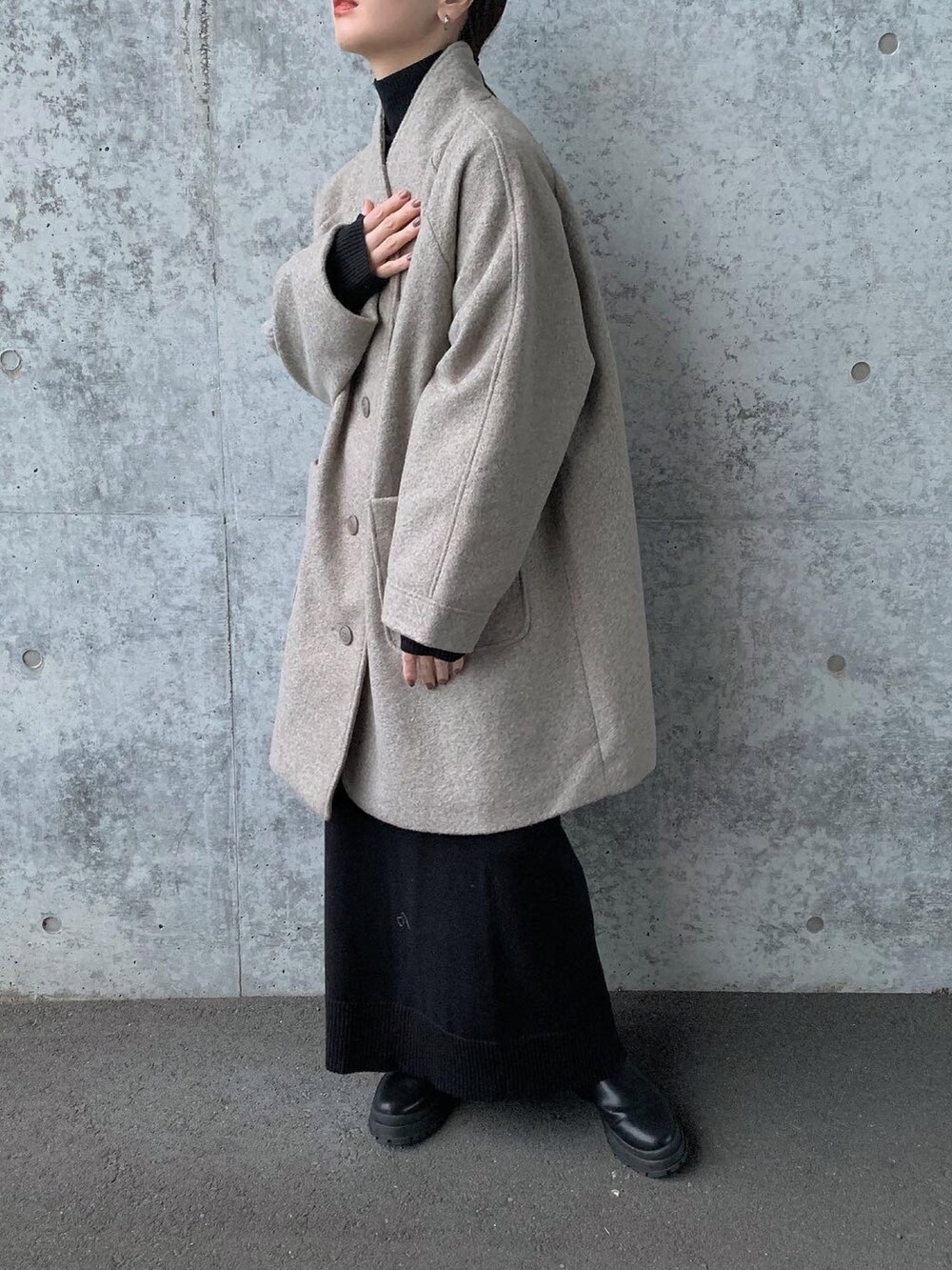 グレー系のノーカラーコート、ブラック系のニット/セーター、ブラック系のスカートを着用したレディースの秋コーディネートの4枚目の写真