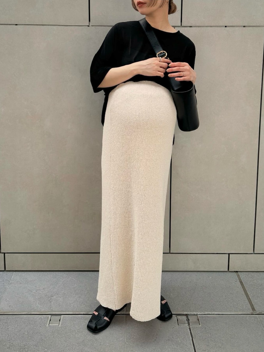 ブラック系のTシャツ/カットソー、ホワイト系のスカート、ブラック系のサンダルを着用したレディースの春コーディネートの4枚目の写真