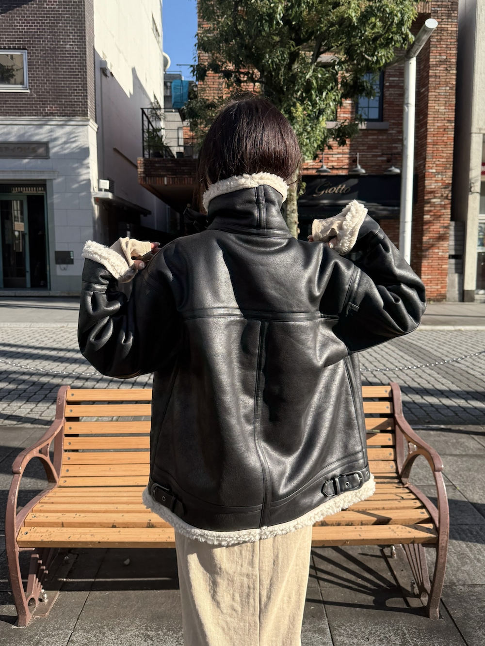 ベージュ系のワンピース、ブラック系のブルゾン、ブラック系のスニーカーを着用したレディースの秋コーディネートの3枚目の写真