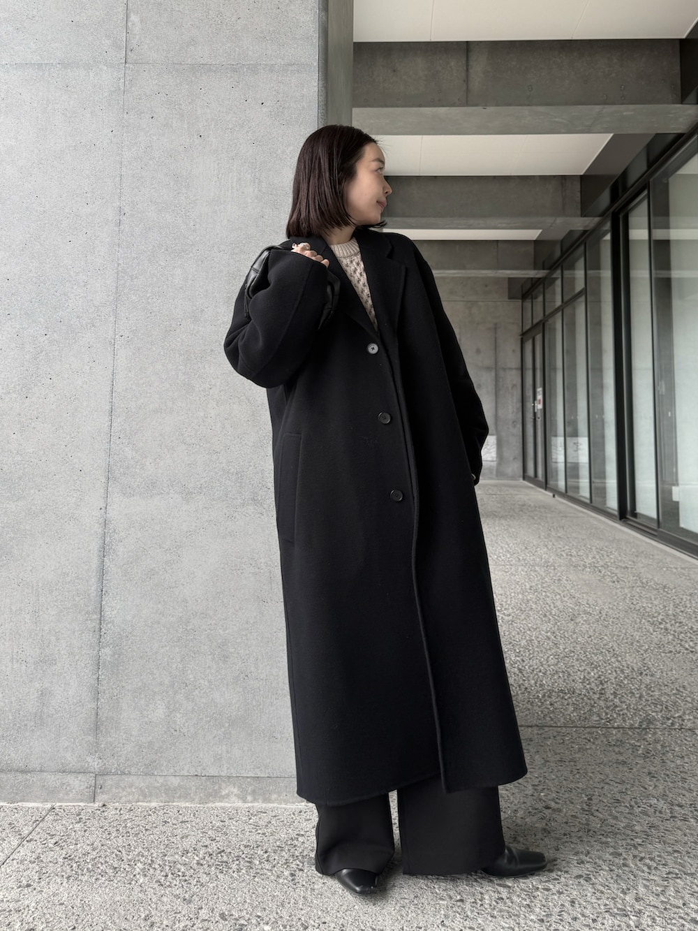 ホワイト系のニット/セーター、ブラック系のチェスターコート、ブラック系のその他パンツを着用したレディースの冬コーディネートの5枚目の写真