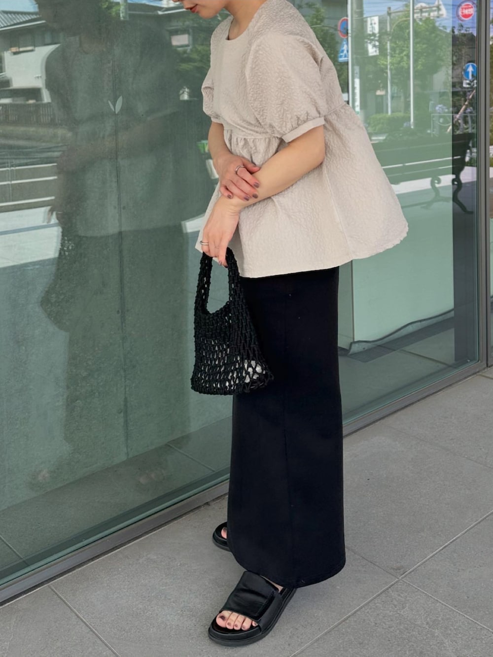 ベージュ系のシャツ/ブラウス、ブラック系のスカート、ブラック系のハンドバッグを着用したレディースの夏コーディネートの3枚目の写真