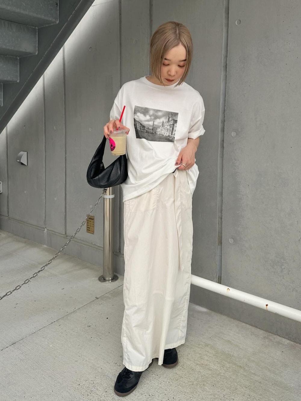 ホワイト系のTシャツ/カットソー、ホワイト系のスカート、ブラック系のスニーカーを着用したレディースの夏コーディネートの2枚目の写真