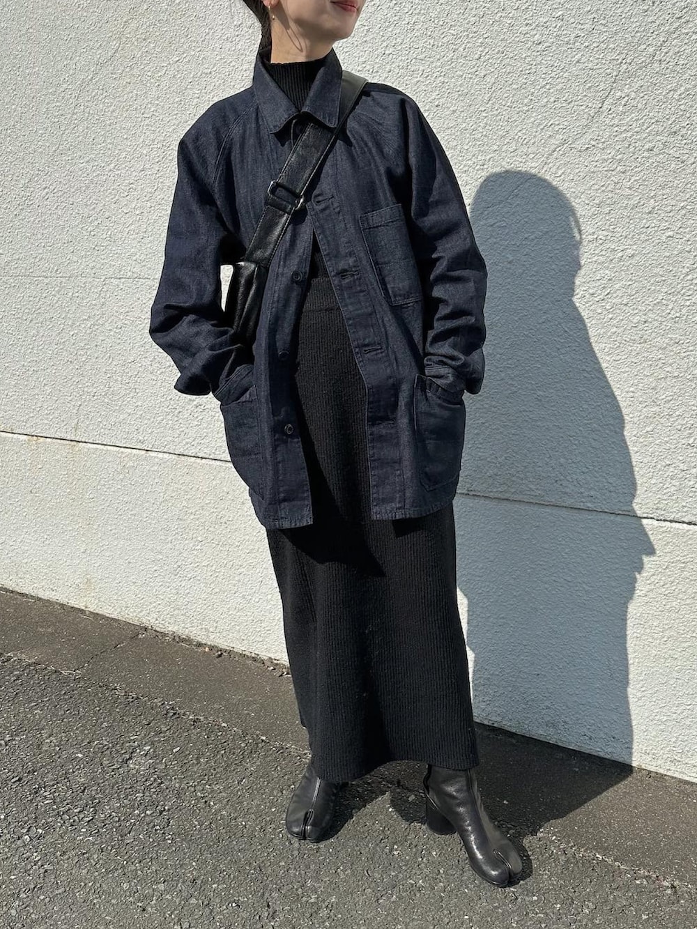 ブルー系のデニムジャケット、ブラック系のショルダーバッグ、ブラック系のニット/セーターを着用したレディースの冬コーディネートの2枚目の写真