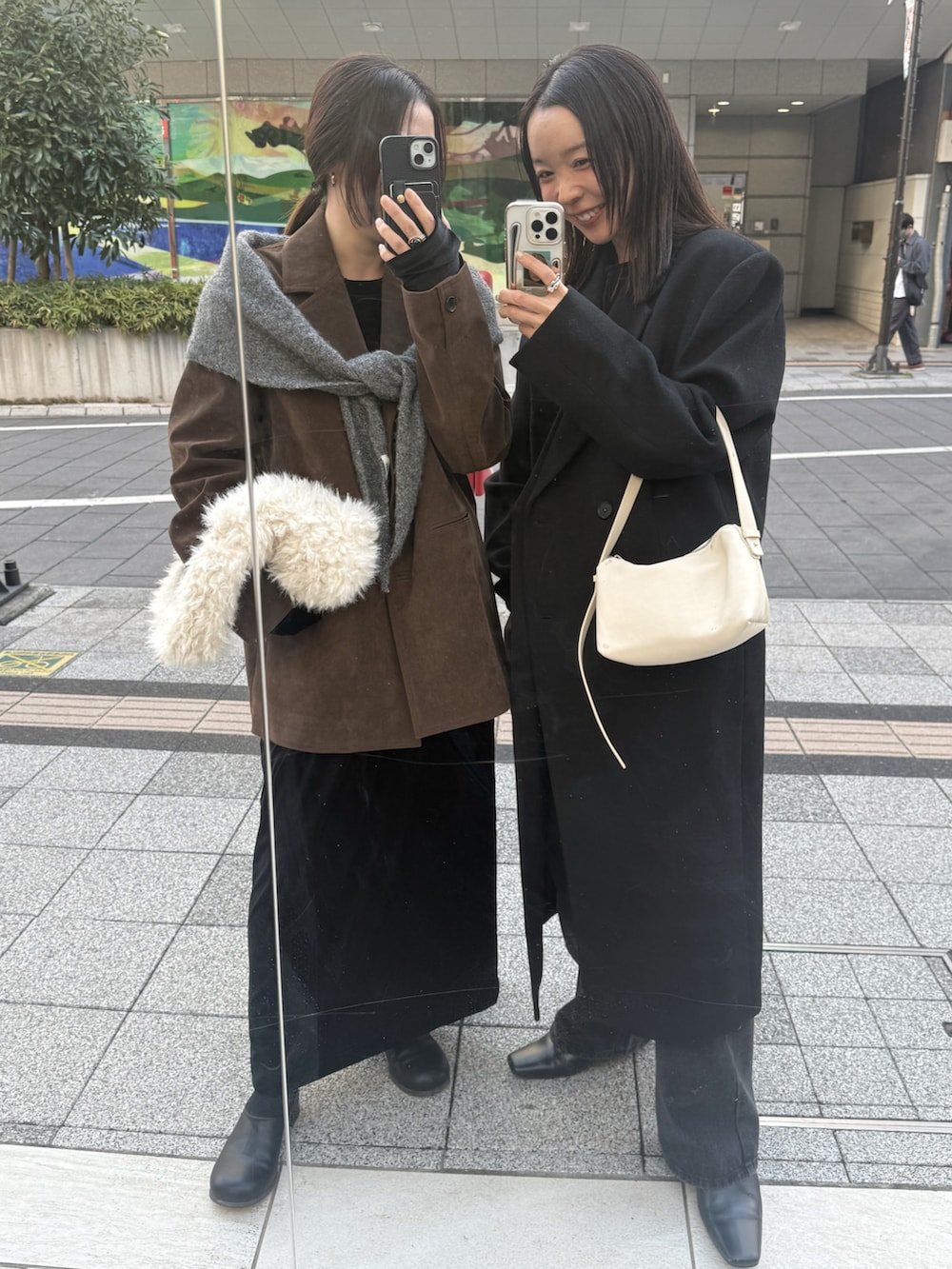 ブラック系のステンカラーコート、ブラック系のニット/セーター、ブラック系のデニムパンツを着用したレディースの秋コーディネートの5枚目の写真