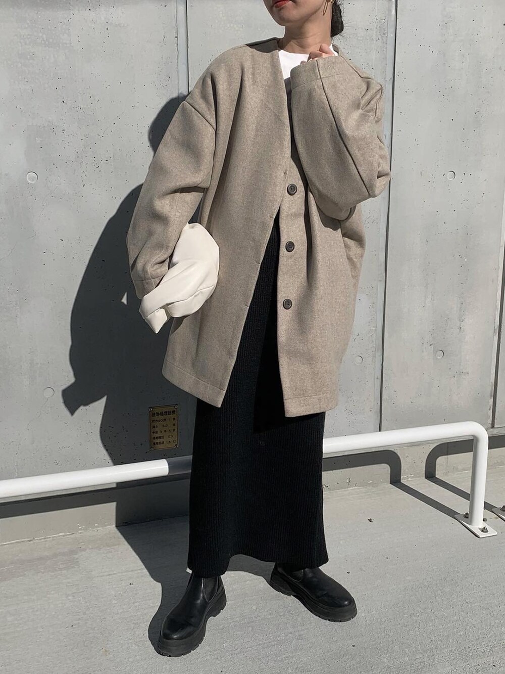 ベージュ系のノーカラーコート、ホワイト系のTシャツ/カットソー、ブラック系のセットアップを着用したレディースの冬コーディネートの5枚目の写真