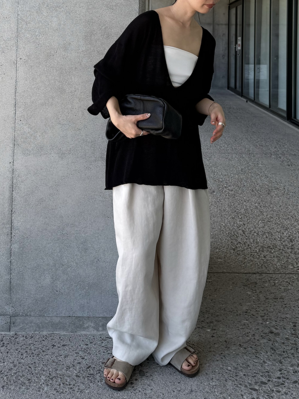 ブラック系のニット/セーター、ホワイト系のその他パンツ、ベージュ系のサンダルを着用したレディースの夏コーディネートの3枚目の写真
