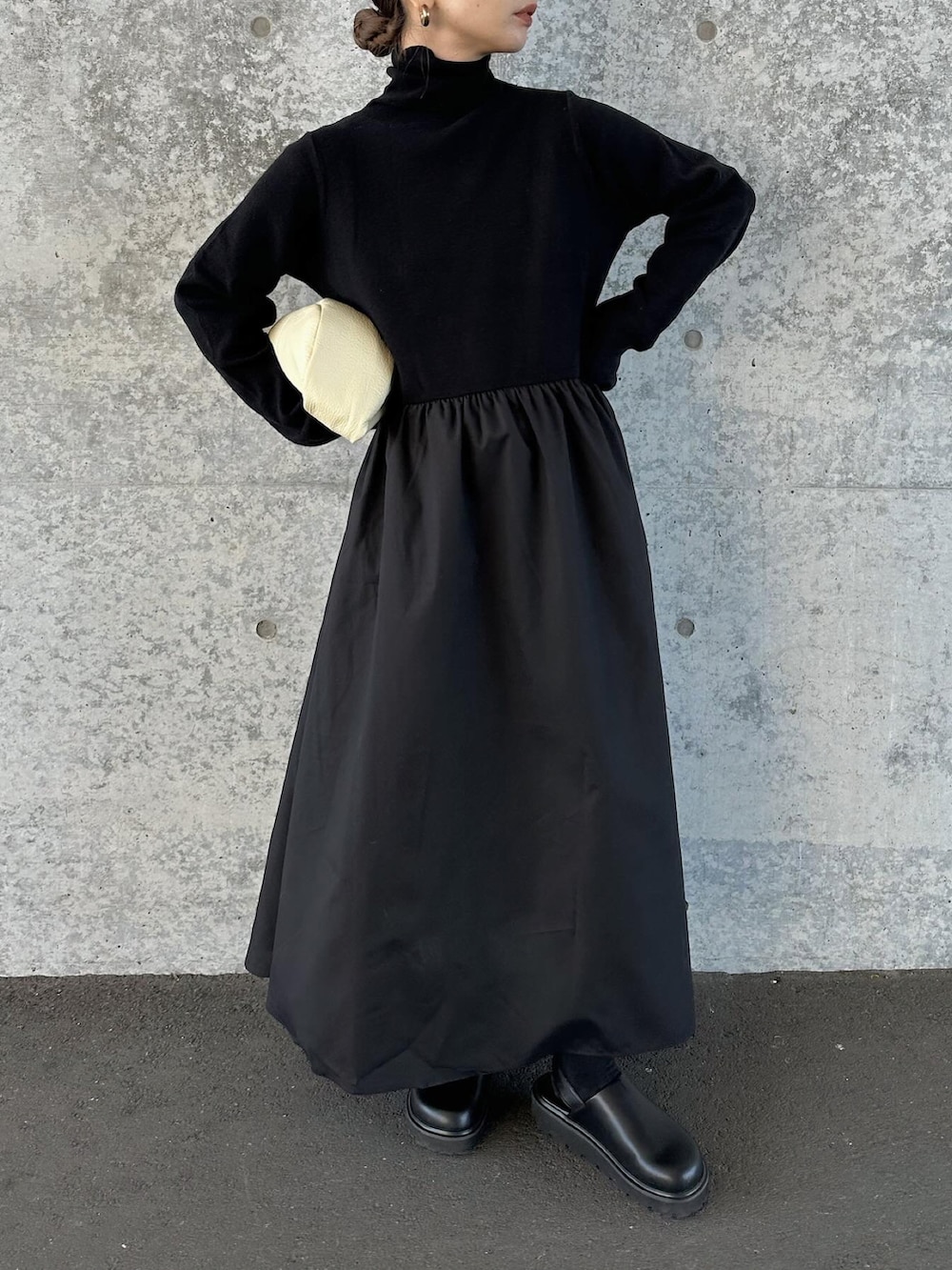 ブラック系のワンピース、ベージュ系のハンドバッグ、ブラック系のスリッポンを着用したレディースの冬コーディネートの4枚目の写真