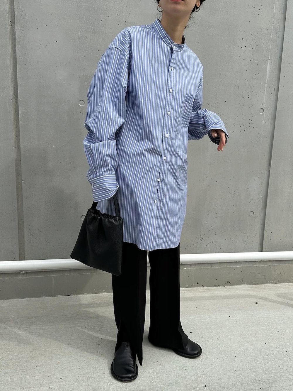 ブラック系のパンツ、ブルー系のシャツ/ブラウス、ブラック系のハンドバッグを着用したレディースの春コーディネートの2枚目の写真