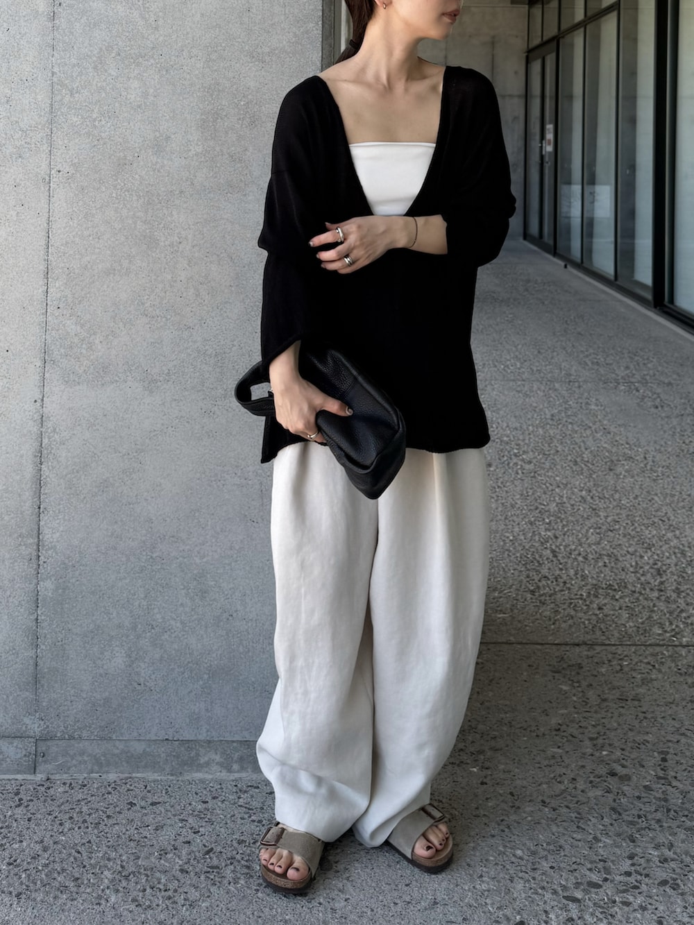 ブラック系のニット/セーター、ホワイト系のその他パンツ、ベージュ系のサンダルを着用したレディースの夏コーディネートの5枚目の写真