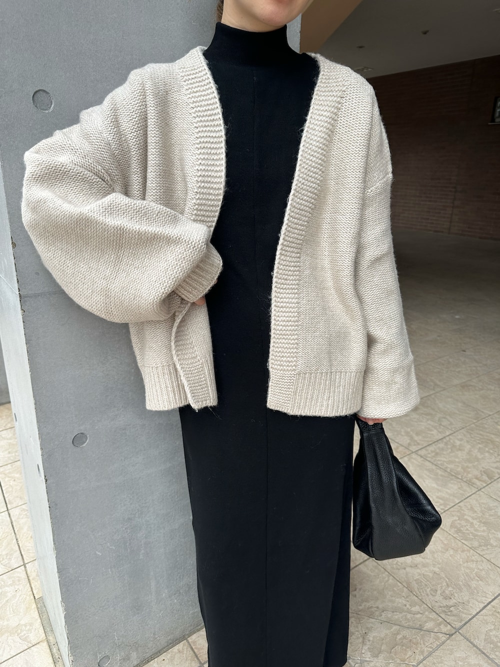 ホワイト系のカーディガン/ボレロ、ブラック系のワンピース、ブラック系のブーツを着用したレディースの秋コーディネートの3枚目の写真