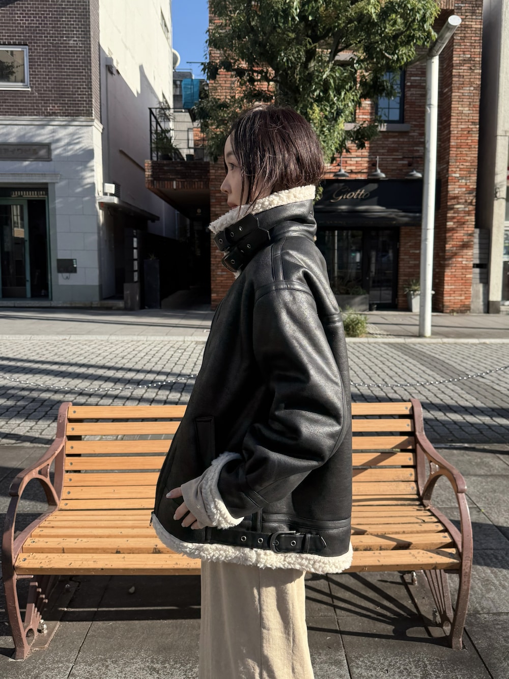 ベージュ系のワンピース、ブラック系のブルゾン、ブラック系のスニーカーを着用したレディースの秋コーディネートの2枚目の写真