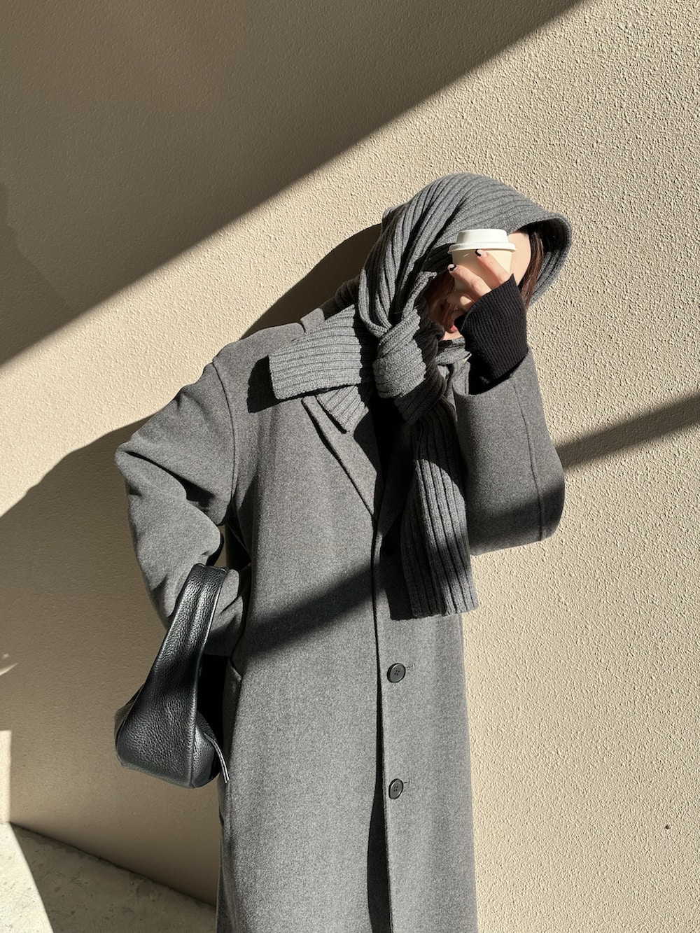 グレー系のステンカラーコート、ブラック系のローファー、ブラック系のハンドバッグを着用したレディースの冬コーディネートの4枚目の写真