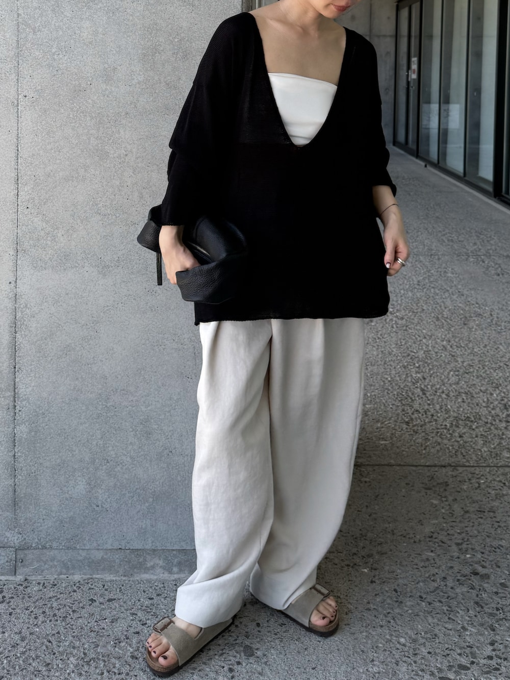 ブラック系のニット/セーター、ホワイト系のその他パンツ、ベージュ系のサンダルを着用したレディースの夏コーディネートの2枚目の写真