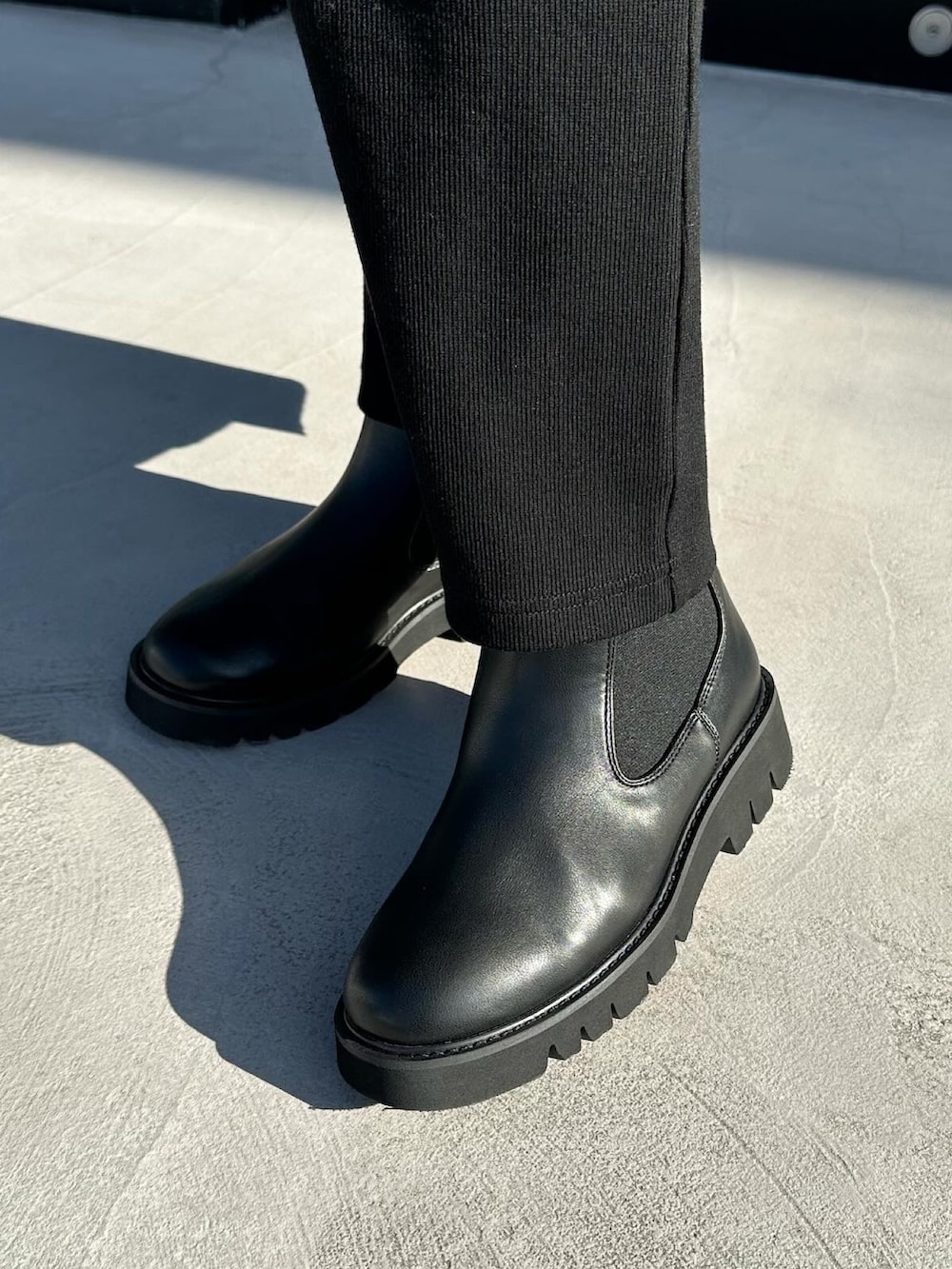 ブラック系のワンピース、ブラック系のハンドバッグ、ブラック系のブーツを着用したレディースの冬コーディネートの3枚目の写真