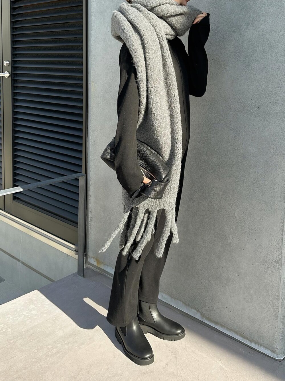 ブラック系のワンピース、ブラック系のハンドバッグ、ブラック系のブーツを着用したレディースの冬コーディネートの5枚目の写真