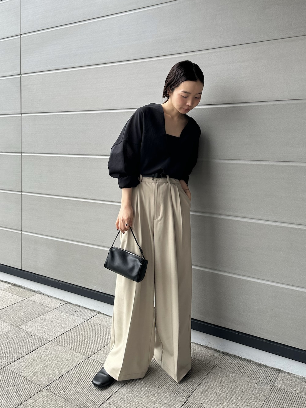 ベージュ系のスラックス、ブラック系のシャツ/ブラウス、ブラック系のスリッポンを着用したレディースの春コーディネートの3枚目の写真