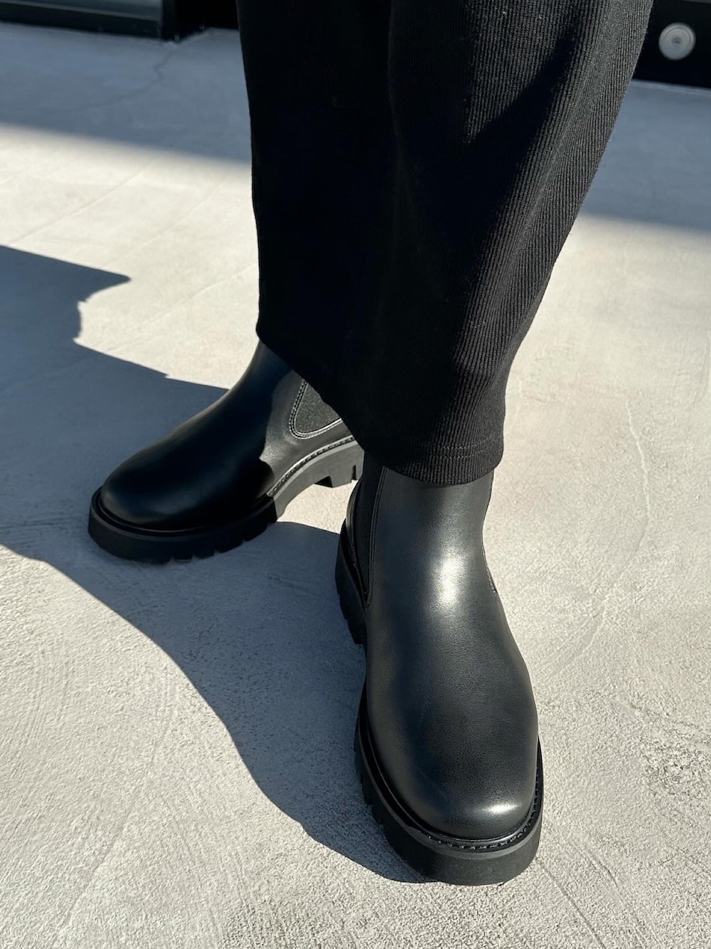 ブラック系のワンピース、ブラック系のハンドバッグ、ブラック系のブーツを着用したレディースの冬コーディネートの2枚目の写真