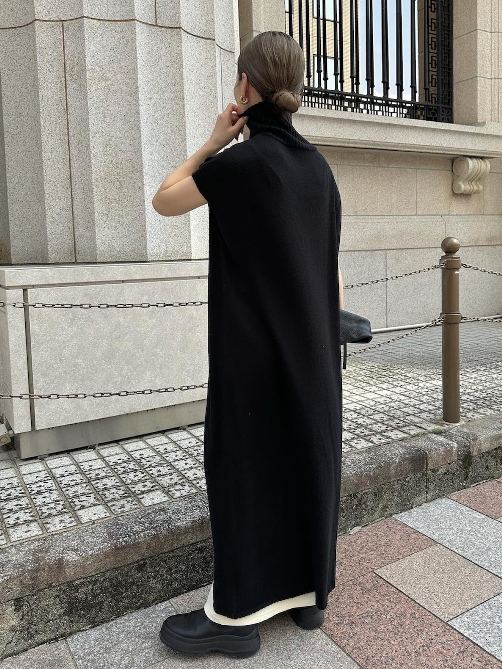 ブラック系のワンピース、ホワイト系のスカート、ブラック系のハンドバッグを着用したレディースの秋コーディネートの5枚目の写真